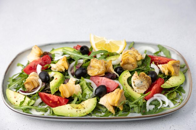 Salade chaude avec des rapans des escargots des tomates des avocats des rogues des olives noires des oignons et de l'huile d'olive Salade traditionnelle de fruits de mer en gros plan