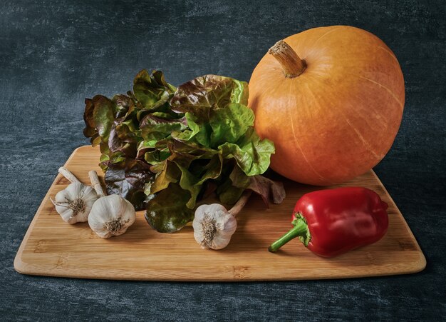 Salade de chêne rouge, citrouille, ail et poivron, légumes sur une planche à découper en bois, style vintage
