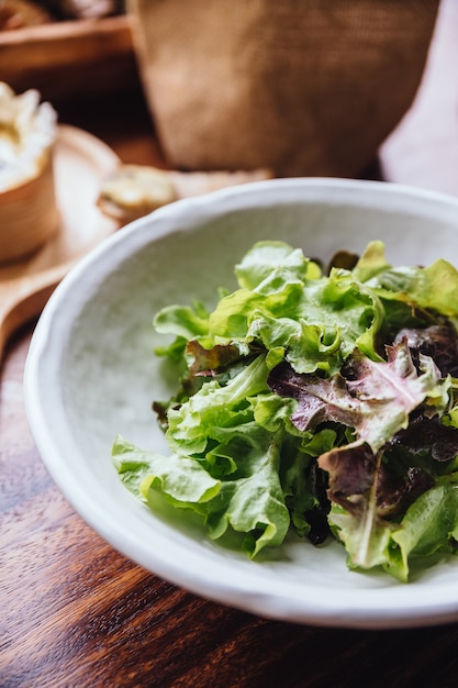 Salade de chêne vert en train de manger avec du Brie sur une planche de bois servie et du pain tranché frais