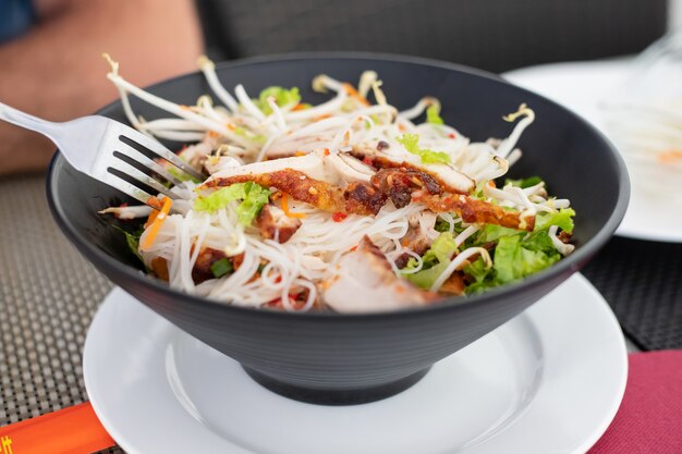 Salade chinoise dans un bol noir au restaurant