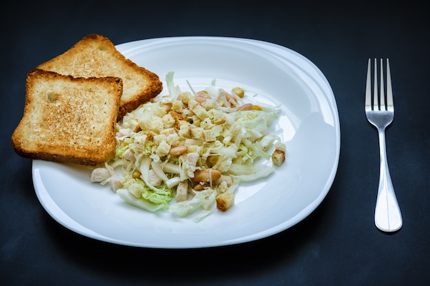 Salade de chou et haricots et croûtons frits sur une plaque blanche