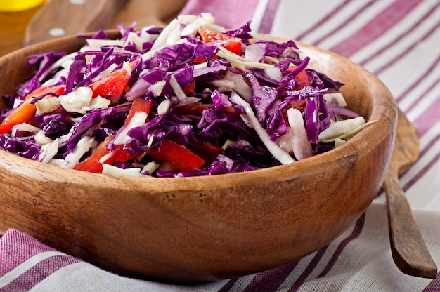 Salade de chou rouge et blanc et de poivron rouge, assaisonnée de jus de citron et d'huile d'olive dans un bol en bois