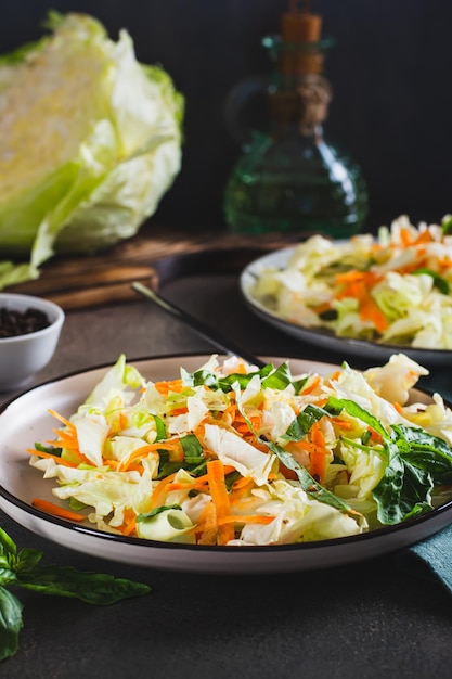 Salade de chou traditionnelle de chou, carottes et légumes verts sur une assiette vue verticale
