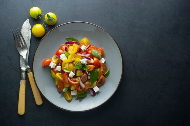 Salade colorée de tomates cerises et basilic dans une assiette. Nourriture saine et d'été.