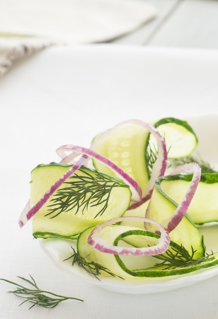 Salade de concombre frais et d'oignons rouges sur fond blanc