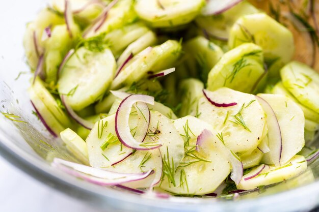 Salade de concombre frais avec tranches de concombre, oignon violet et aneth frais dans un bol en verre.