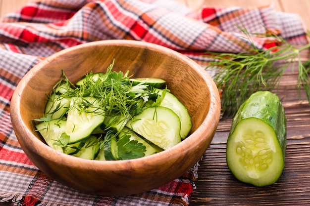 Salade de concombres aux herbes dans une assiette en bois