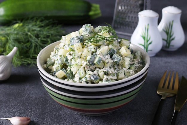 Salade de courgettes au fromage à l'ail et à l'aneth dans un bol sur fond gris foncé Gros plan