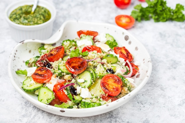 Salade de couscous méditerranéen avec tomates cerises frites, concombre et sauce pesto