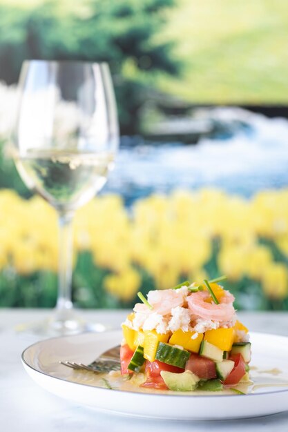 Photo salade de crabe et de crevettes servie avec du vin blanc contre un jardin à l'accent doux