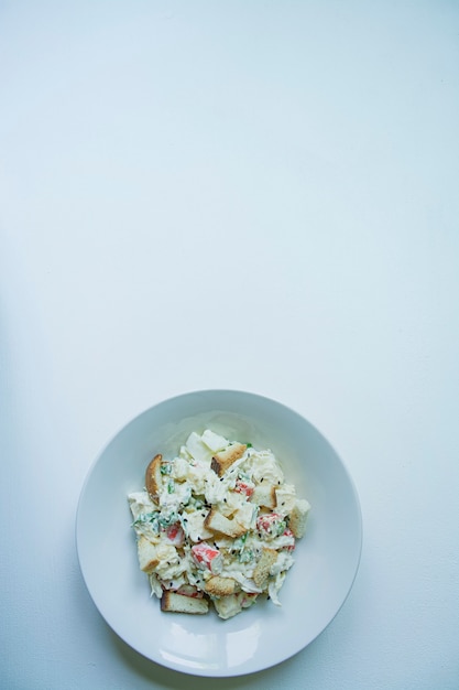 Salade avec craquelins, bâtonnets de crabe, filet de poulet, légumes verts frais et fromage à pâte dure