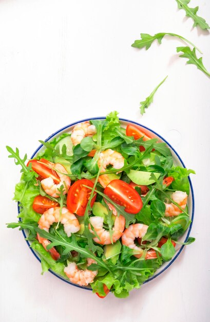 Salade de crevettes d'été avec tomates laitue roquette concombre avocat et vinaigrette au citron sur fond blanc Une saine alimentation des aliments propres