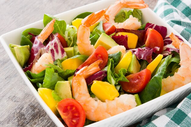 Salade de crevettes à la mangue et à l'avocat sur table en bois se bouchent