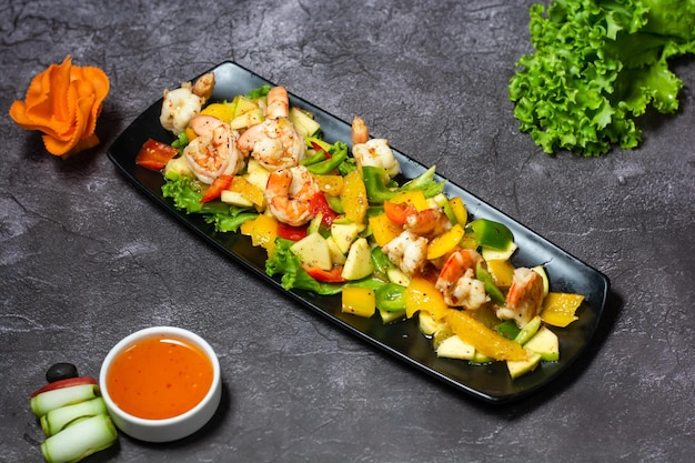 Salade de crevettes avec tomate orange concombre pomme et sauce servie dans un plat isolé sur fond gris vue de dessus de la nourriture indienne et bangladaise