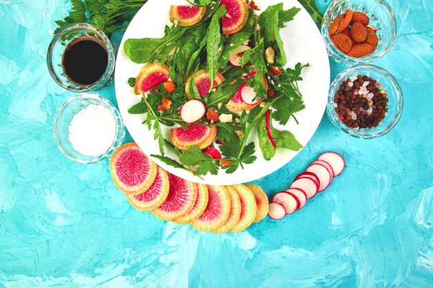 Salade dans une assiette blanche autour d'ingrédients mélange de radis en feuilles