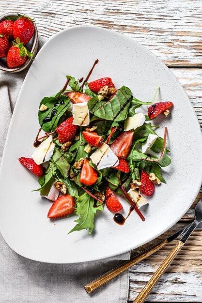 Salade diététique au brie, fraises, noix, blettes et roquette. Fond blanc. Vue de dessus