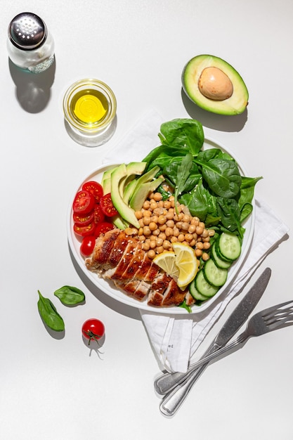 Salade diététique au poulet avocat concombre tomate et épinards sur fond blanc Mise à plat Lumière dure