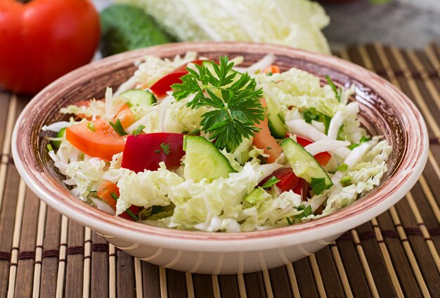 Salade diététique aux légumes frais (chou, poivron, tomate, concombre) dans un bol en céramique