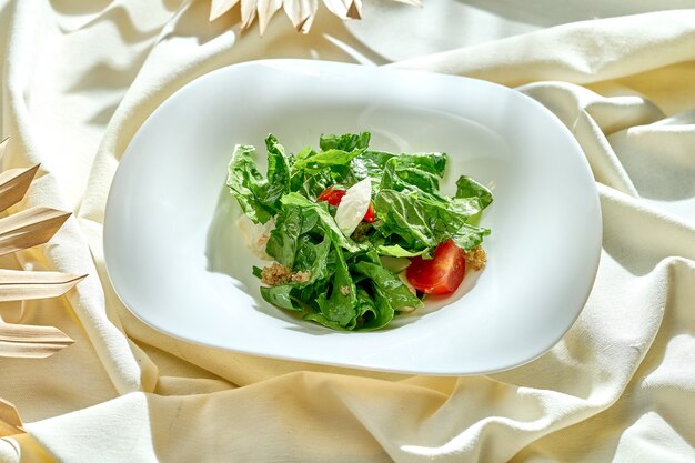 Salade diététique aux tomates et au quinoa dans une assiette blanche sur une nappe