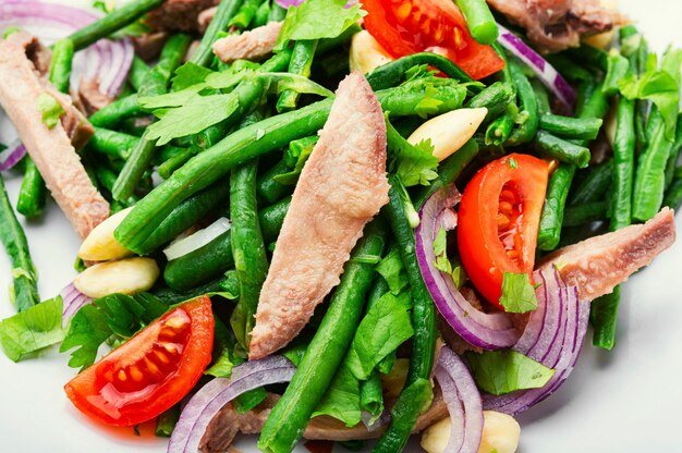 Salade diététique avec langue de veau, asperges, tomates et herbes. Salade saine avec langue de bœuf tranchée