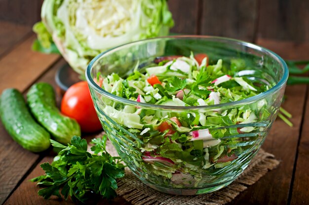 Salade diététique saine de légumes frais dans un bol en verre sur une table en bois.