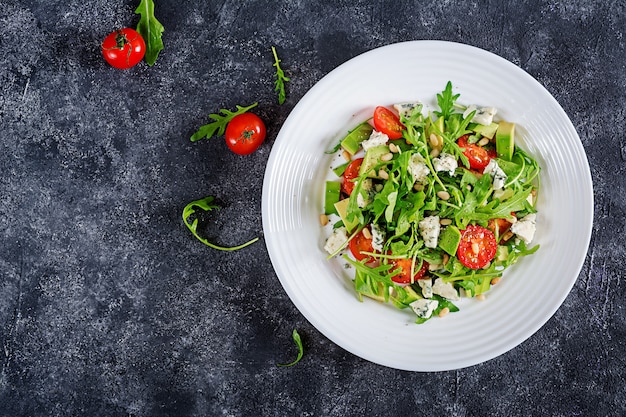 Salade diététique avec tomates, fromage bleu, avocat, roquette et pignons de pin. Vue de dessus. Lay plat.