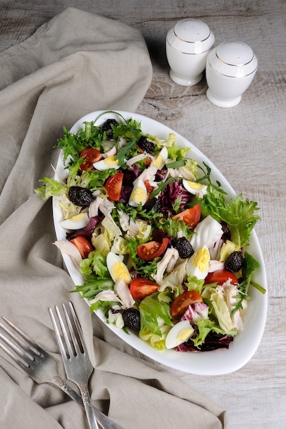 salade du mélange de feuilles de laitue avec tomates oeufs tranches de poitrine de poulet et olives séchées