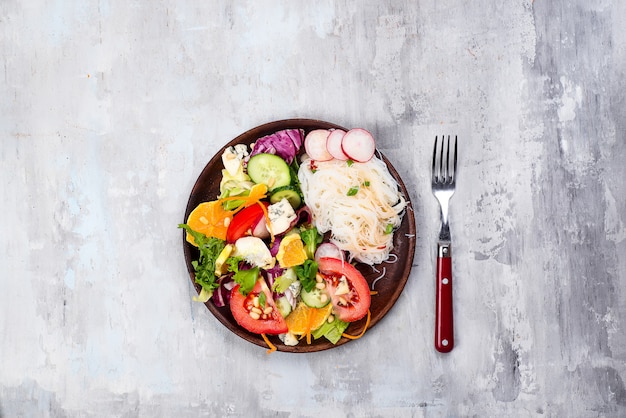 Salade épicée asiatique de nouilles de verre ou de funchoza avec salade de carottes et de légumes sur fond de pierre