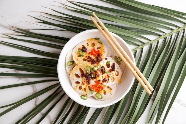 Salade épicée de racine de lotus sur le fond en pierre blanche, nourriture asiatique