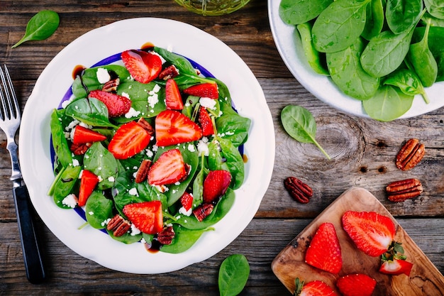 Salade d'épinards aux fraises fromage feta balsamique et noix de pécan sur fond de bois