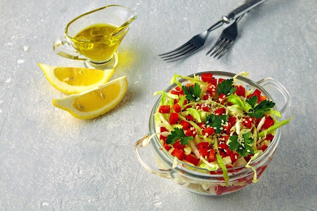 Salade d'été un apéritif léger de chou blanc et de poivron avec du persil dans un bol en verre sur une table en pierre grise