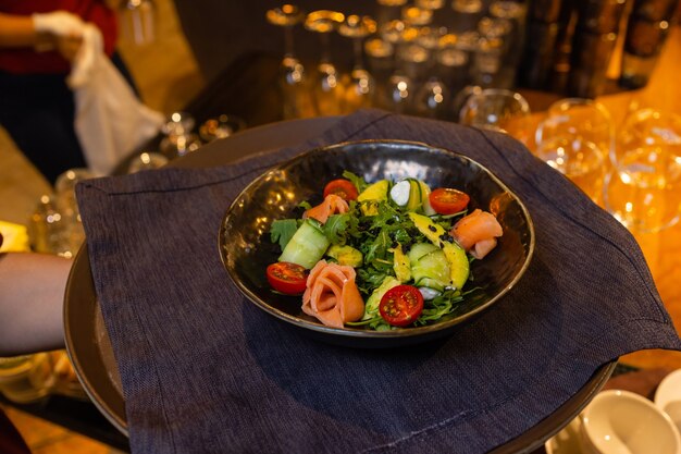 Salade d'été sur une assiette blanche avec un serveur à la main.