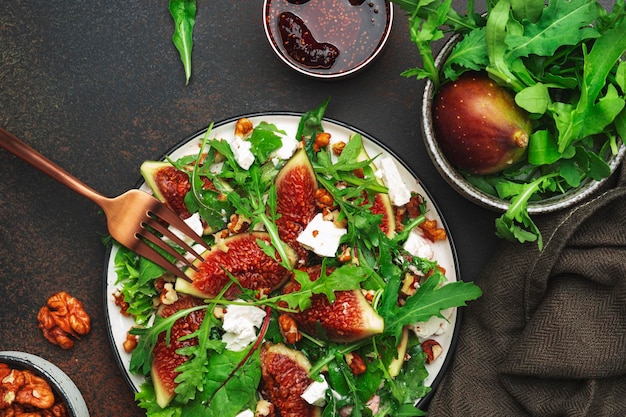 Salade d'été aux figues fromage blanc noix bette à carde et roquette avec vinaigrette à la confiture sur fond marron vue de dessus copie espace