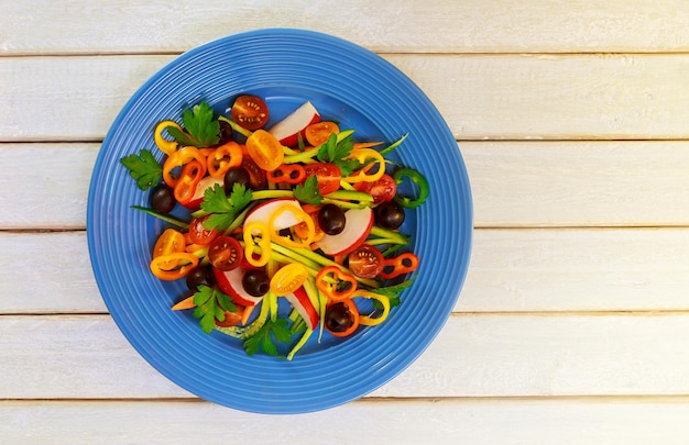 Salade d'été aux tomates en plaque blanche sur table en bois