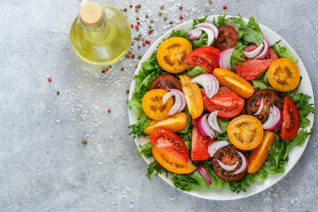 Salade d'été délicieuse de tomates colorées, d'oignons rouges et de laitue aux épices