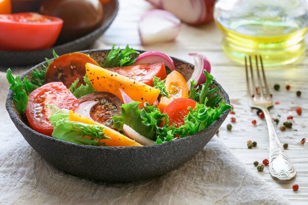 Salade d'été délicieuse de tomates colorées, d'oignons rouges et de laitue aux épices