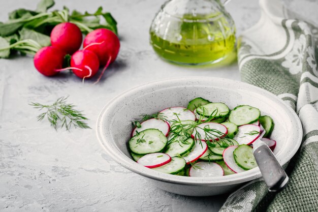 Salade d'été fraîche avec radis et concombre oignons verts et aneth dans un bol