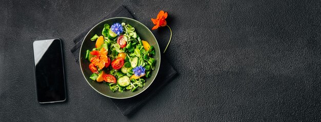 Photo salade d'été végétalienne et smartphone sur fond noir