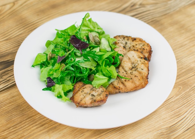 Salade de feuilles et de viande grillée sur un fond en bois