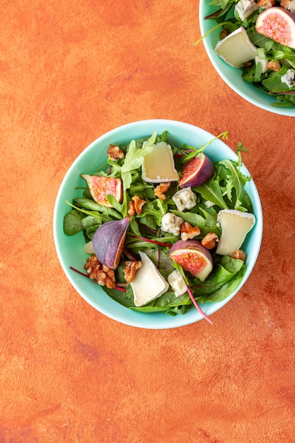 Photo salade de figues fraîches avec roquette, fromage et noix sur fond orange. vue de dessus