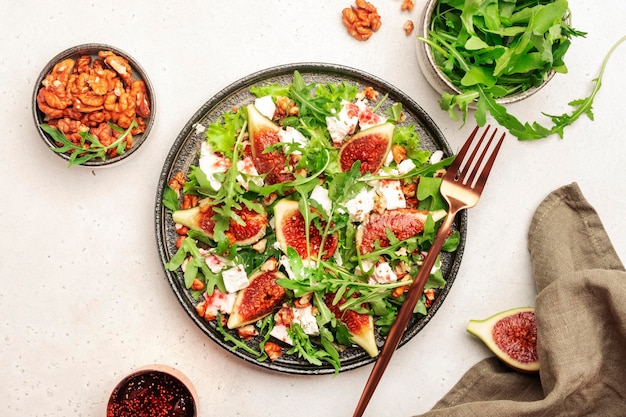 Salade de figues sucrées avec fromage de chèvre doux noix roquette et vinaigrette à la confiture sur fond blanc vue de dessus copie espace