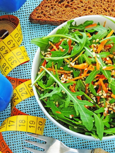 Salade de fitness délicieuse et nutritive avec des carottes de roquette et du sésame. Le concept de perte de poids et de style de vie sportif