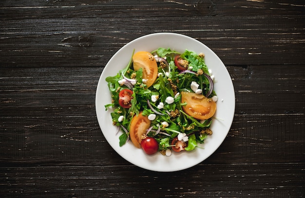 Salade fraîche aux tomates, légumes verts mélangés, noix, œufs, sur fond de bois. Nourriture saine.