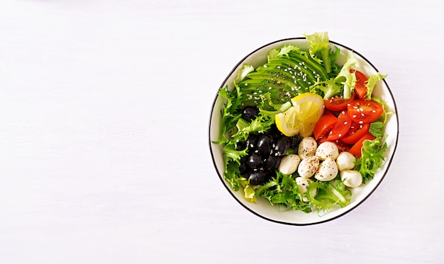 Salade fraîche d'avocat, tomate, olives et mozzarella dans un bol.