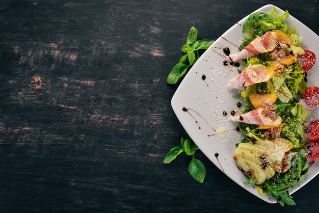 Salade fraîche avec bacon, avocat et tomates Sur un fond en bois Vue de dessus Espace de copie