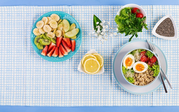 Salade fraîche avec flocons d'avoine, tomates, laitue, micro-légumes et oeuf à la coque et assiette de fruits