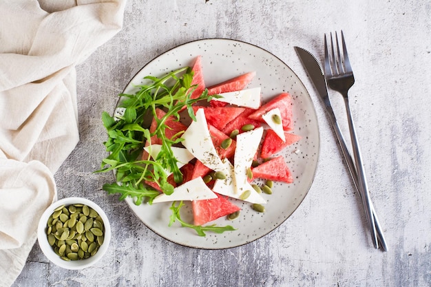 Salade fraîche de melon d'eau fromage feta roquette et graines de citrouille sur une assiette Alimentation biologique Vue de dessus