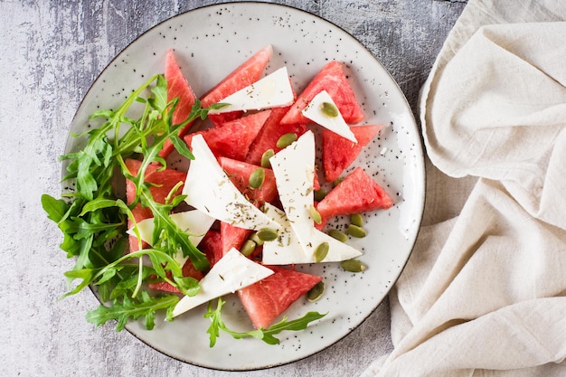 Salade fraîche de melon d'eau fromage feta roquette et graines de citrouille sur une assiette Vue de dessus Gros plan