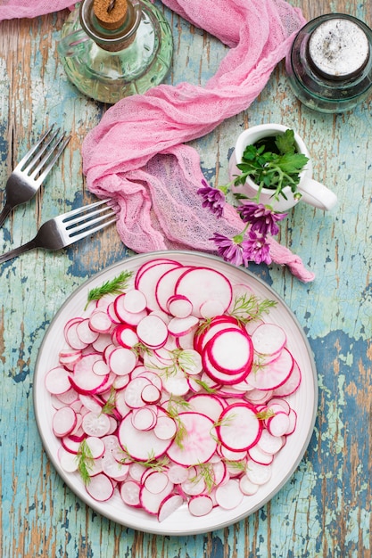 Salade fraîche de morceaux de radis et d'aneth sur une assiette sur une table en bois. Prêt collation pour un régime. Vue de dessus