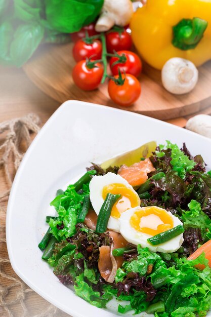Salade fraîche avec des œufs pochés et des légumes servie sur une table en bois